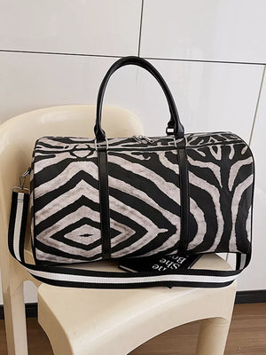 Large black and white zebra print duffle bag with carry handles and detachable strap.