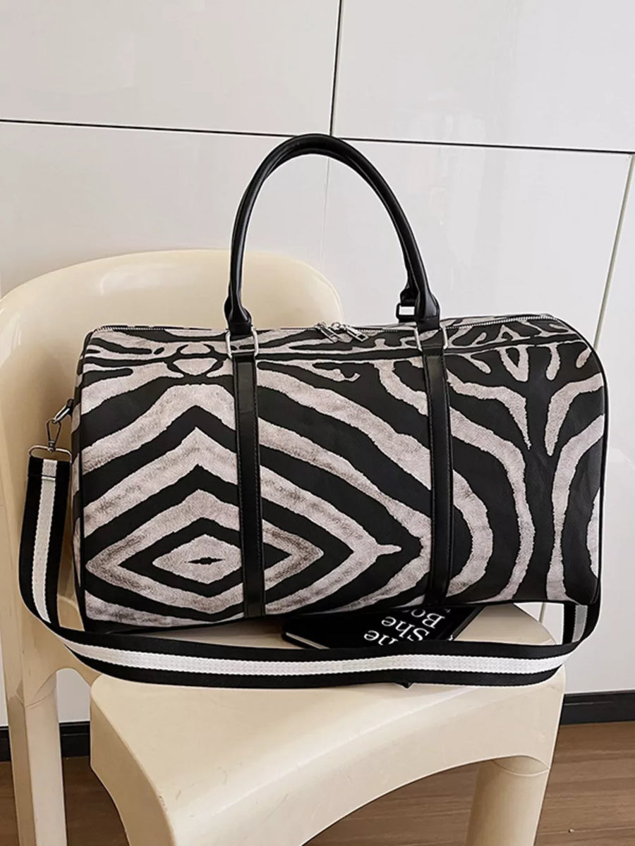 Large black and white zebra print duffle bag with carry handles and detachable strap.