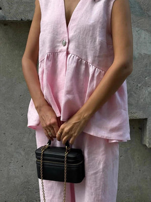 Sleeveless pink linen blend peplum top with V-neck and button detail, paired with wide-leg pants.