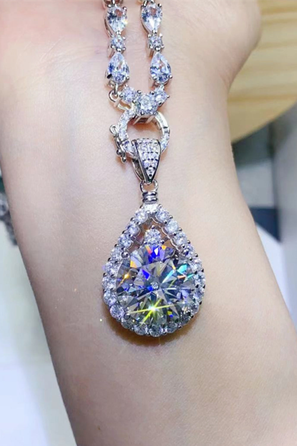 Silver halo moissanite pear drop necklace with a large center stone and intricate detailing.