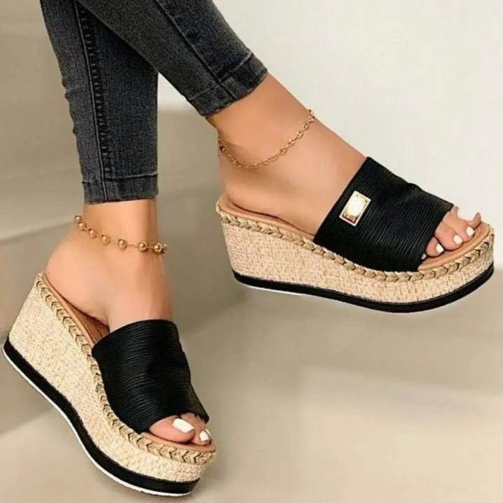 Black textured platform slides with metallic detail and espadrille wedge.