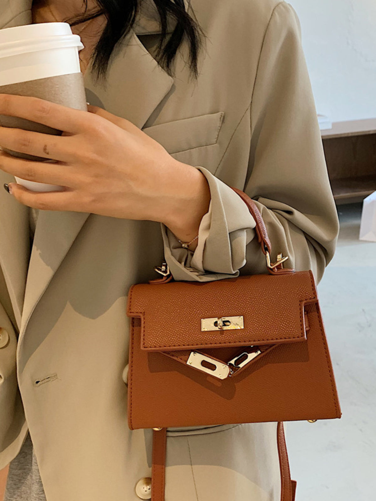 Brown mini crossbody bag in faux leather with gold hardware and a top handle.