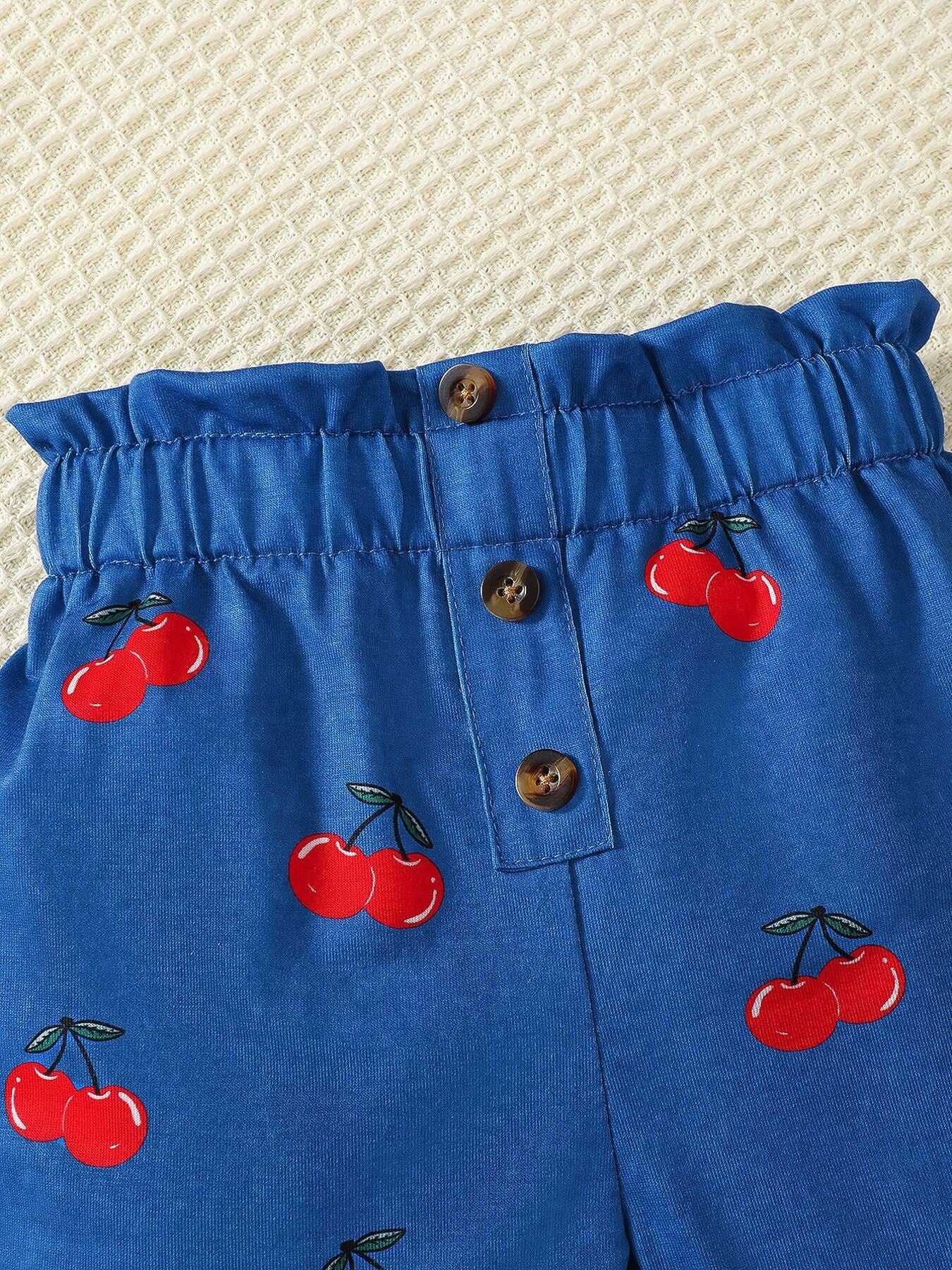 Blue cherry print shorts with ruffled waist and button detail
