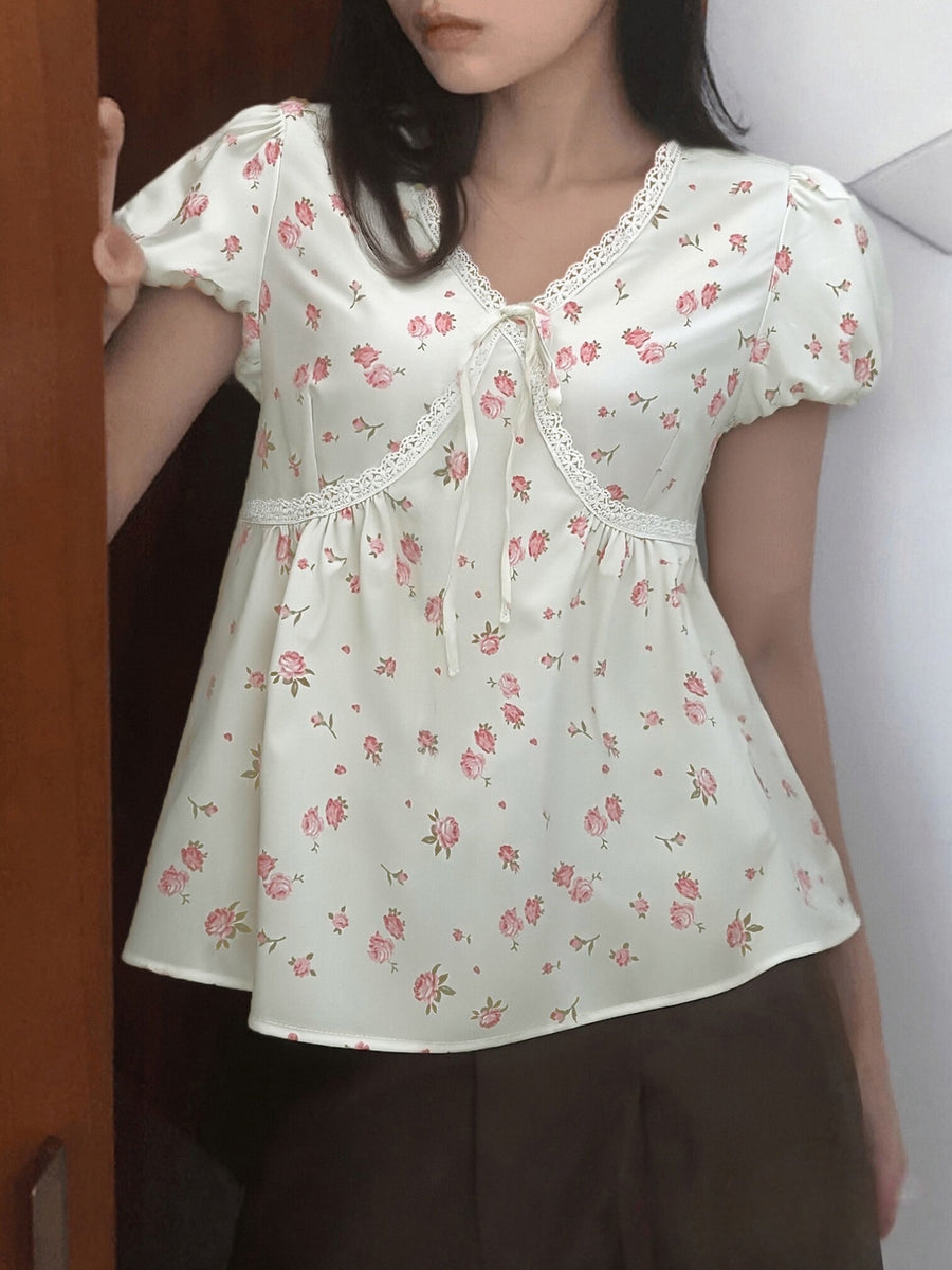 Cream floral blouse with lace trim, tie-neck, and puff sleeves.