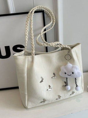 Cream shopper bag with braided handles, butterfly details, and cloud charm.