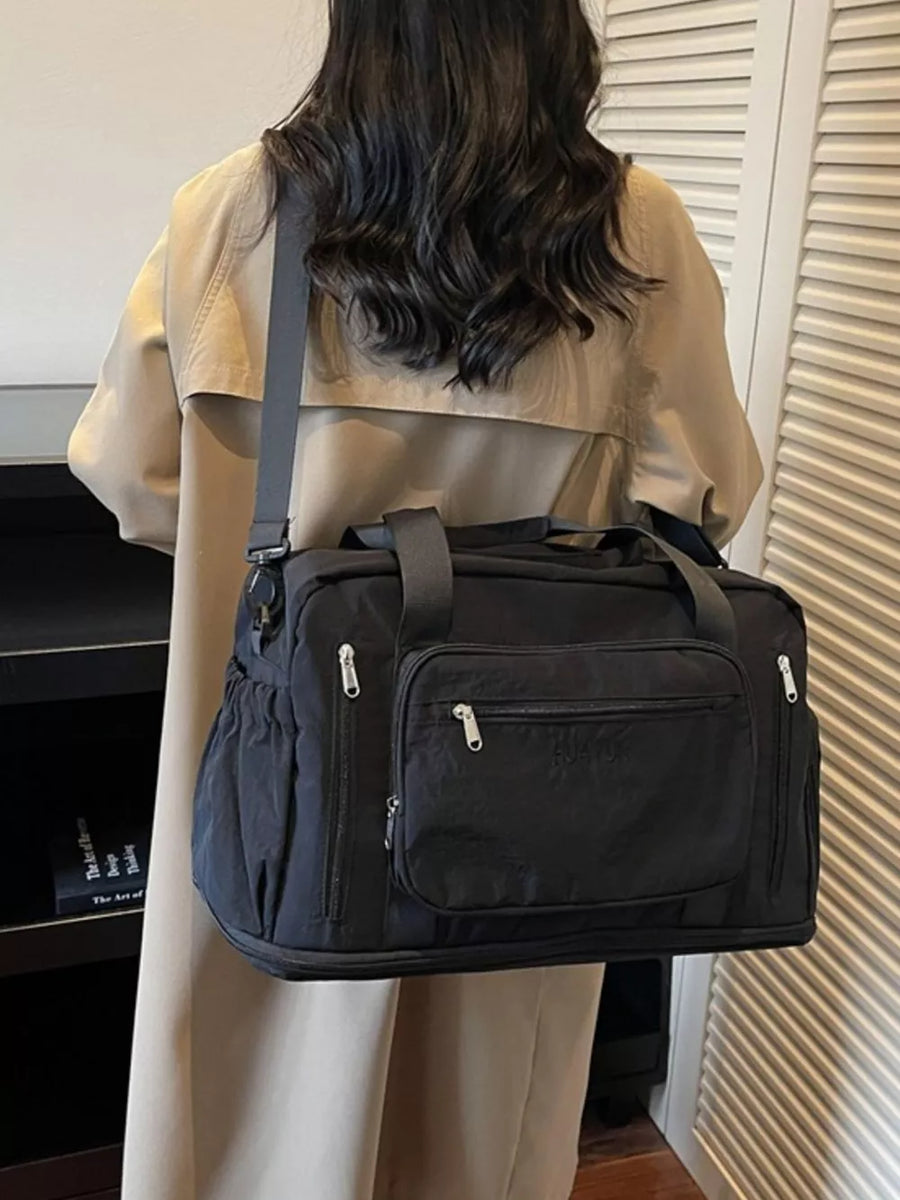 Black canvas duffel bag with multiple zippered pockets and adjustable strap.