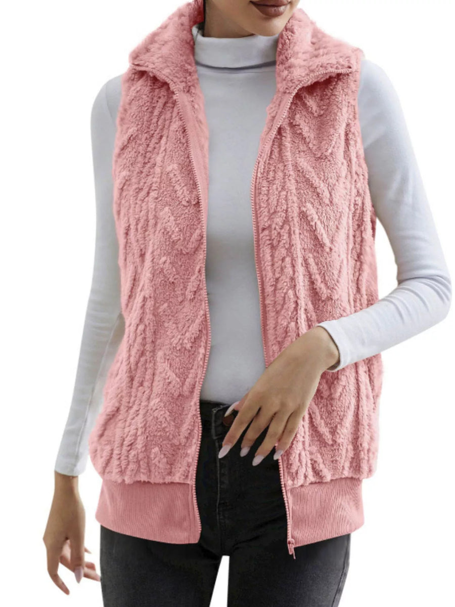 Pink faux fur zip-up vest with textured pattern and ribbed hem.