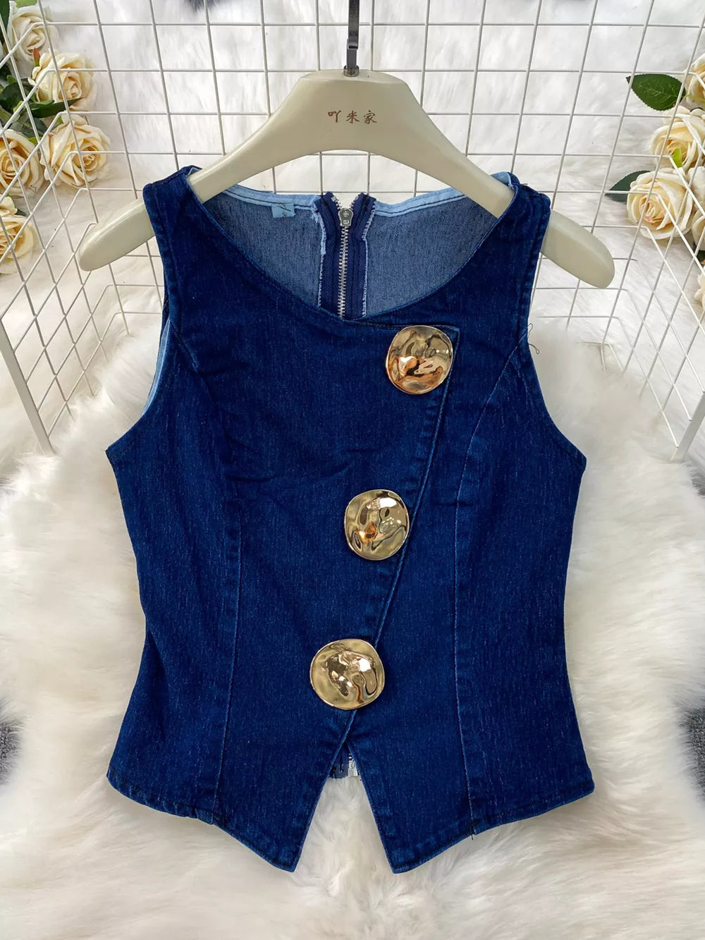 Dark blue cotton denim vest with asymmetrical gold buttons and zipper detail.