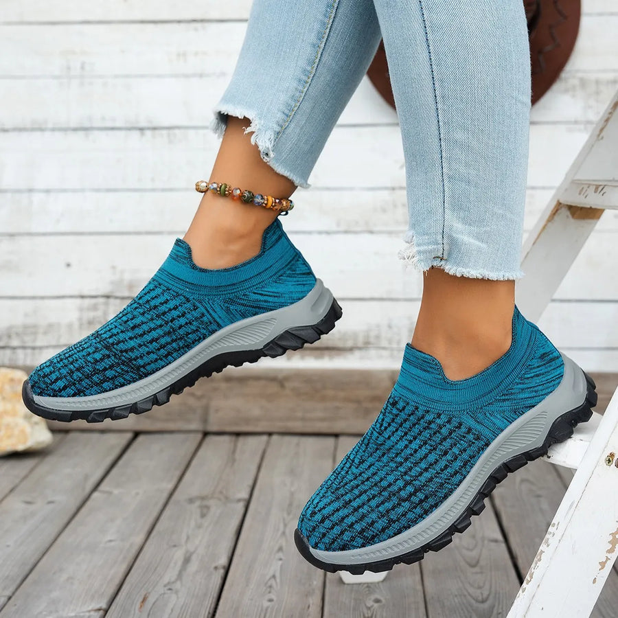 Cerulean textured knit slip-on sneakers with black accents and grey soles.