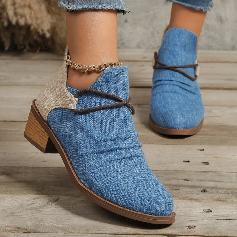 Cerulean denim ankle boots with ruched detail, contrast heel, and chain accent.