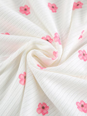 White ribbed knit fabric with pink floral print, detail shot