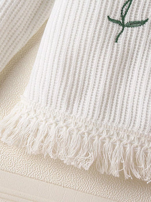 White waffle knit baby top with floral applique and fringe hem