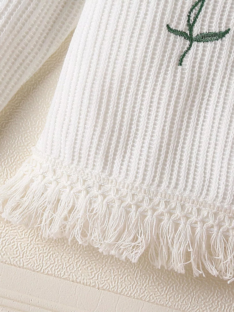 White waffle knit baby top with floral applique and fringe hem