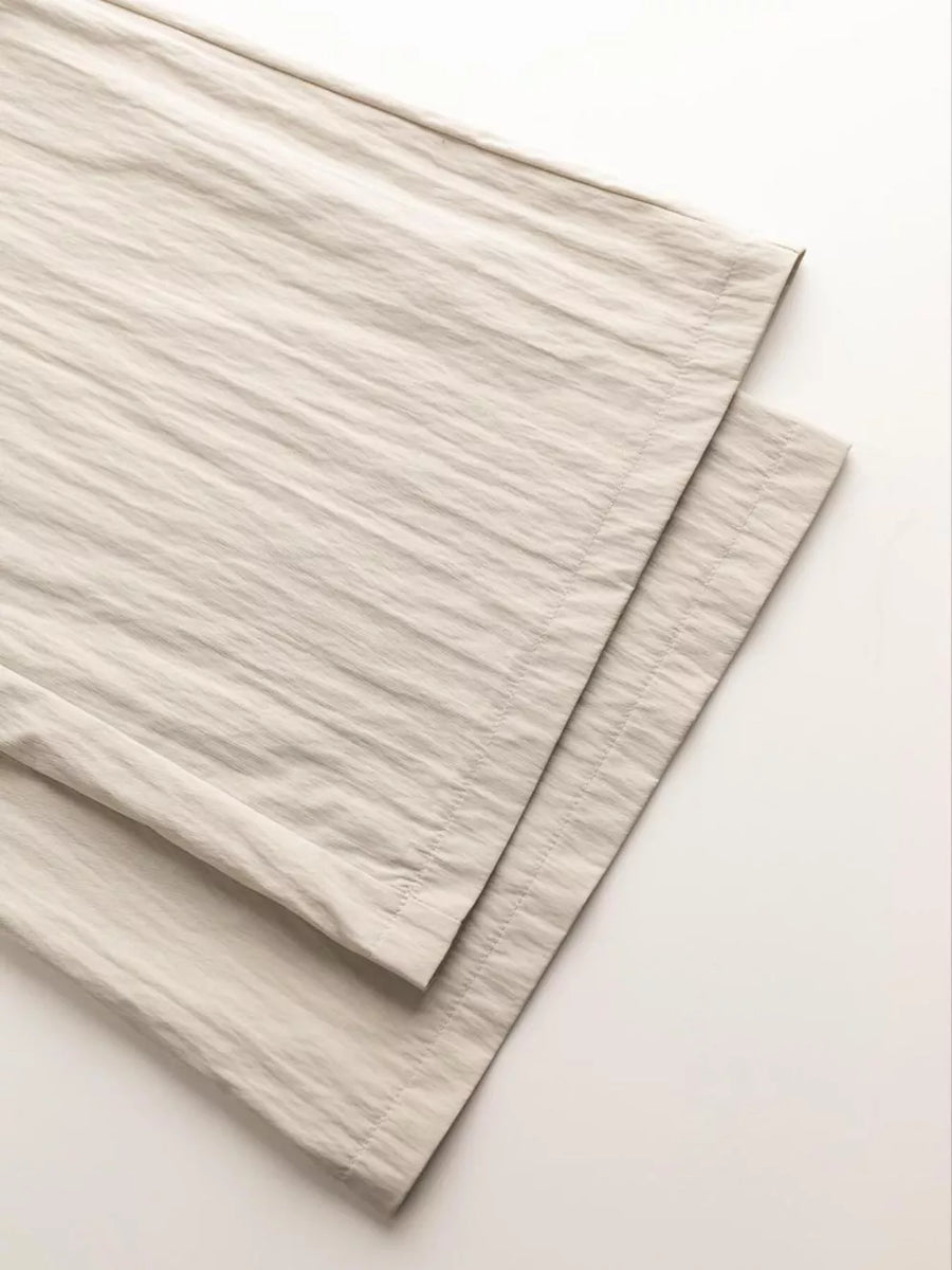 Beige wide-leg pants with textured fabric and visible stitching detail