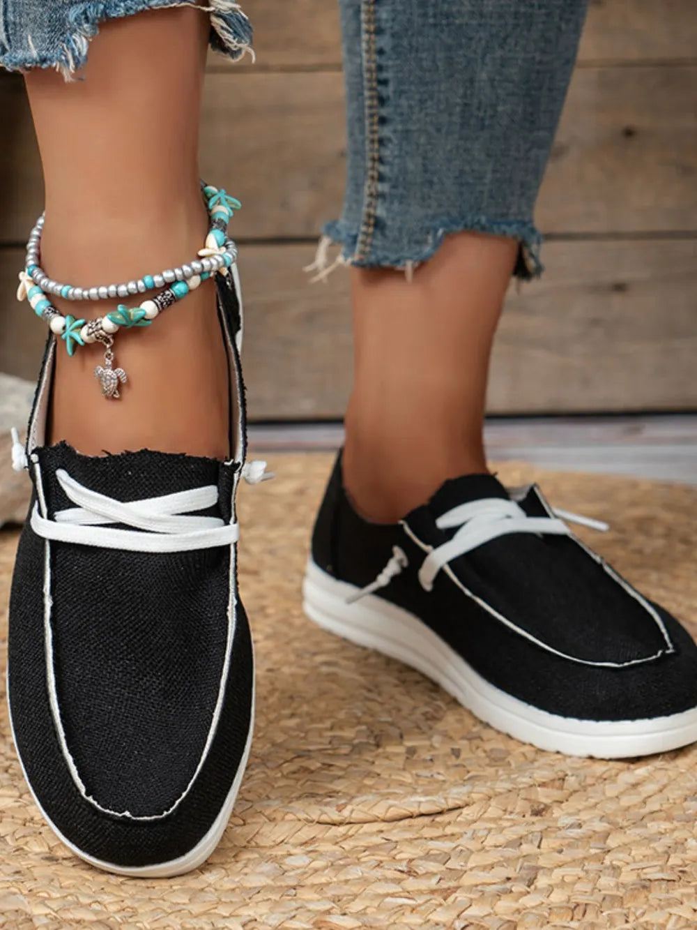 Black canvas boat shoes with white contrast stitching and laces.