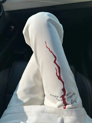 White sweatpants with red graphic detail and text print on leg