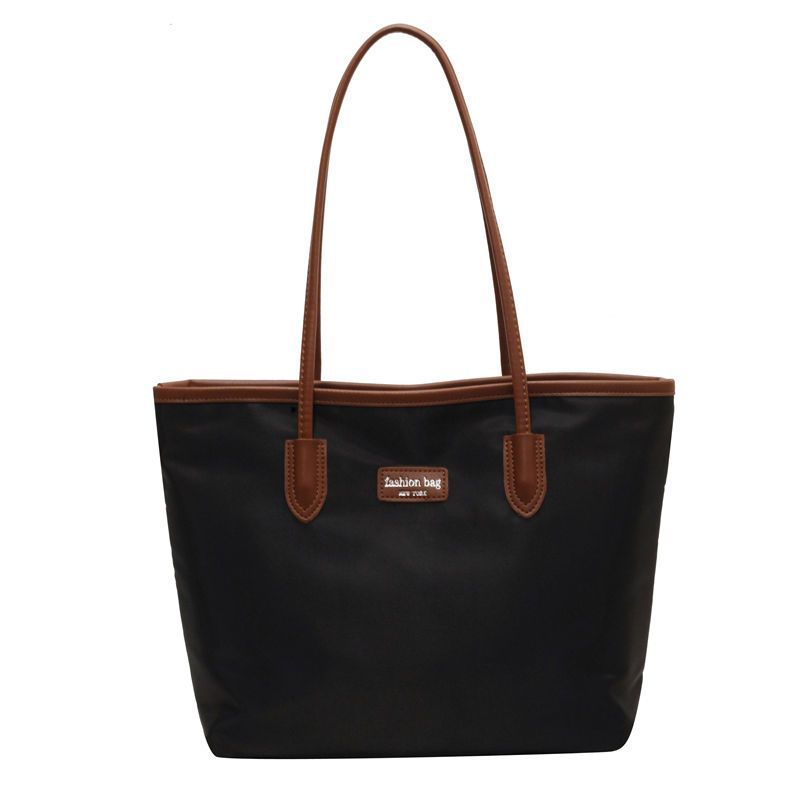 Large black Oxford cloth tote bag with brown trim and handles.