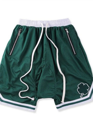 Dark green mesh basketball shorts with white drawstring, zipper pockets, and clover logo detail.