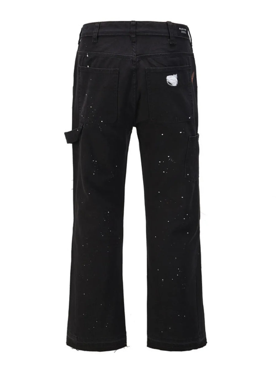 Black carpenter trousers with white paint splatters and distressed detail.