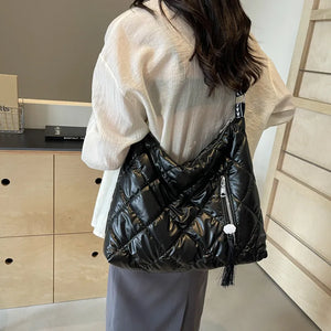 Black diamond quilt padded shoulder bag with tassel detail and zipper pocket.