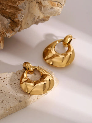 Gold statement earrings with sculpted, textured teardrop shape and open center.