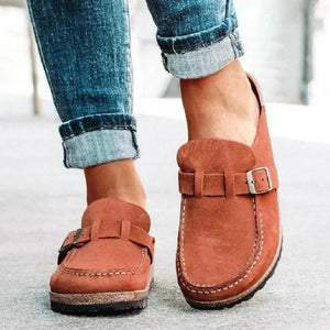 Suede buckle mule loafers in caramel with visible stitching detail.