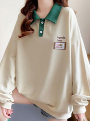 Apricot waffle knit polo sweatshirt with green collar and button placket.