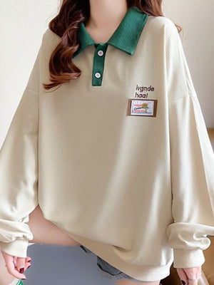 Apricot waffle knit polo sweatshirt with green collar and button placket.