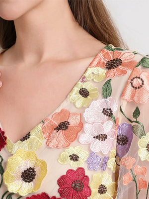 Sheer mesh top with colorful floral embroidery and V-neckline.