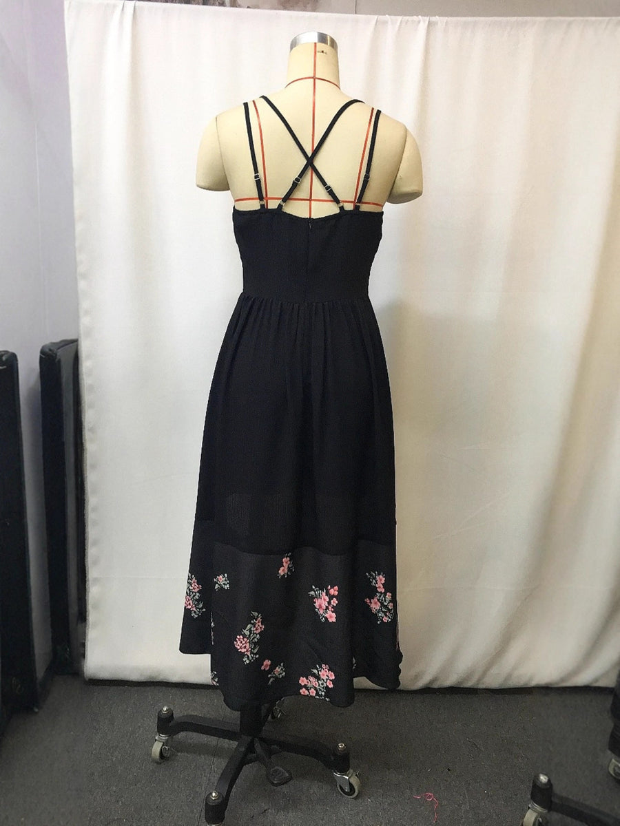 Black floral high-low cami dress with crisscross straps and floral hem detail.