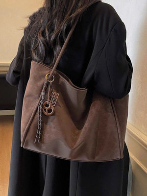 Brown suede shoulder bag with braided rope and charm detail
