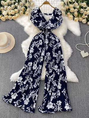 Dark Blue floral pleated wide-leg romper with V-neck and flutter sleeves.