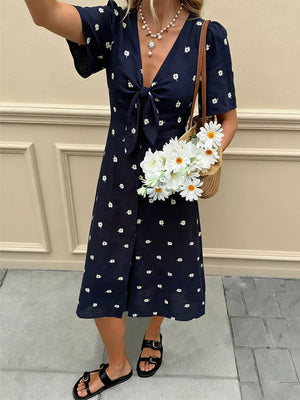 Navy blue daisy print midi dress with tie-front and flutter sleeves.