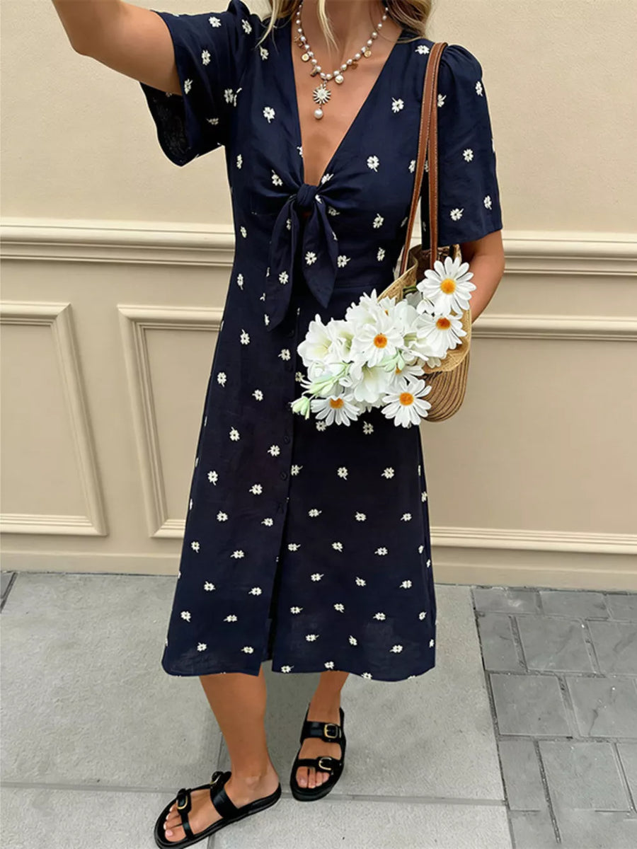 Navy blue daisy print midi dress with tie-front and flutter sleeves.