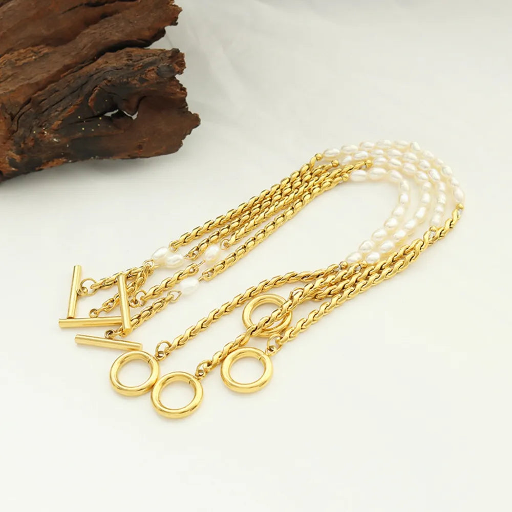 Gold bracelet with multiple chains, pearls, and toggle clasp detail.