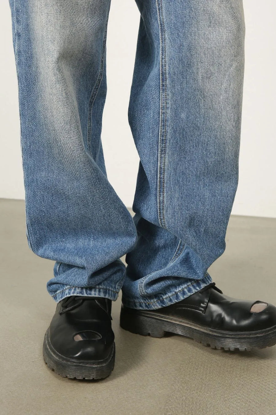 Vintage wash baggy denim jeans in medium blue, styled with black platform shoes.