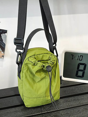 Green nylon drawstring shoulder bag with adjustable strap and top handle.