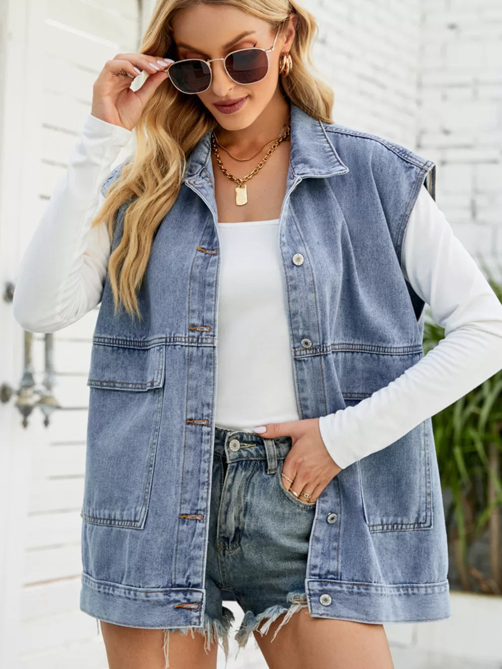 Relaxed-fit sleeveless denim vest in light blue with button-down front and chest pockets.