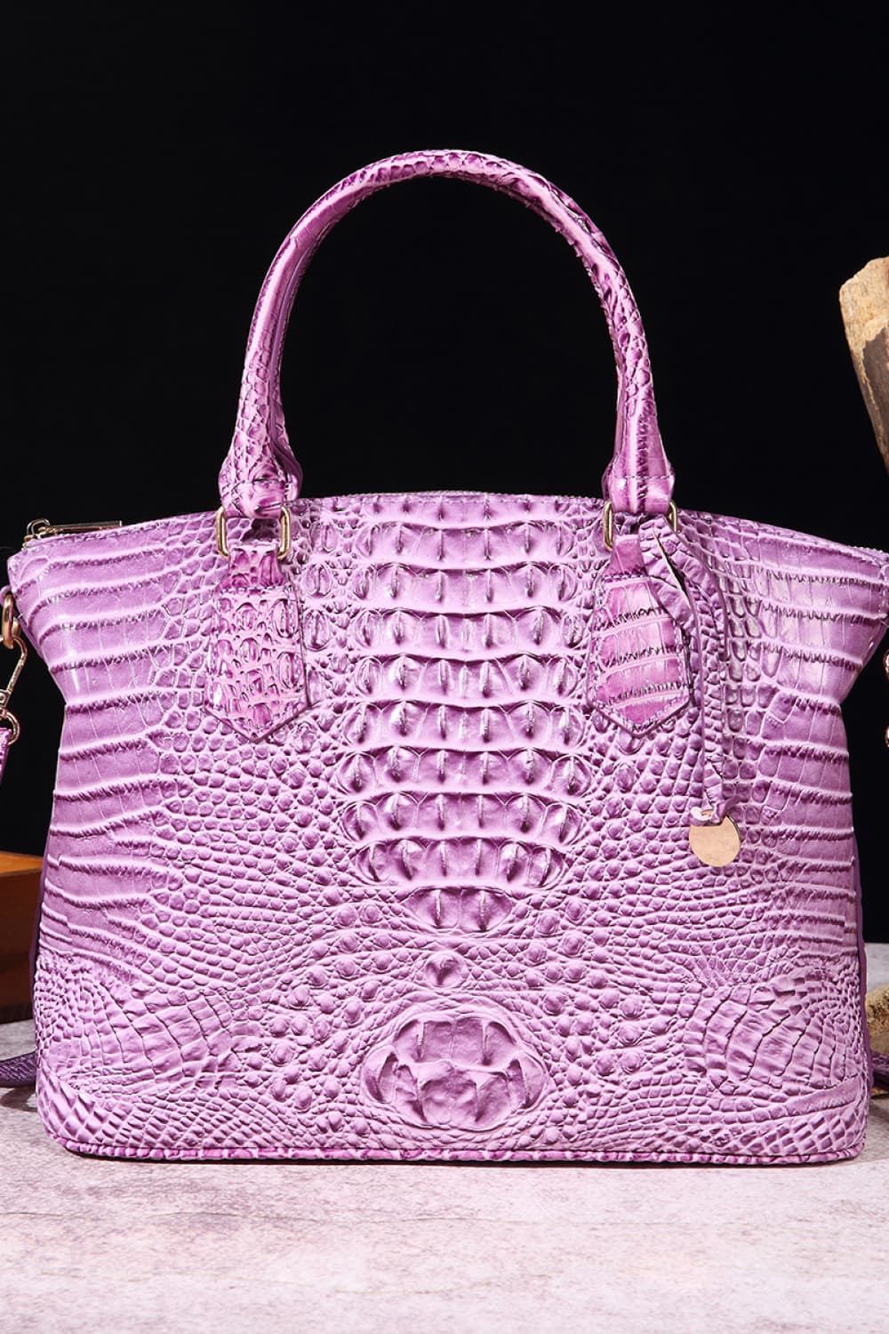 Lilac crocodile embossed satchel bag with top handles and shoulder strap.