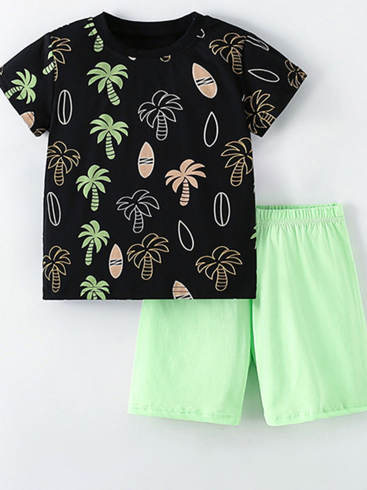 Black cotton tee with tropical palm tree and surfboard print, paired with light green shorts.