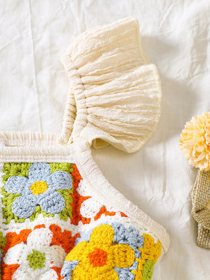 Crochet baby jumpsuit with ruffle trim and colorful floral granny squares.