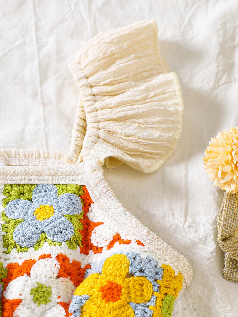 Crochet baby jumpsuit with ruffle trim and colorful floral granny squares.