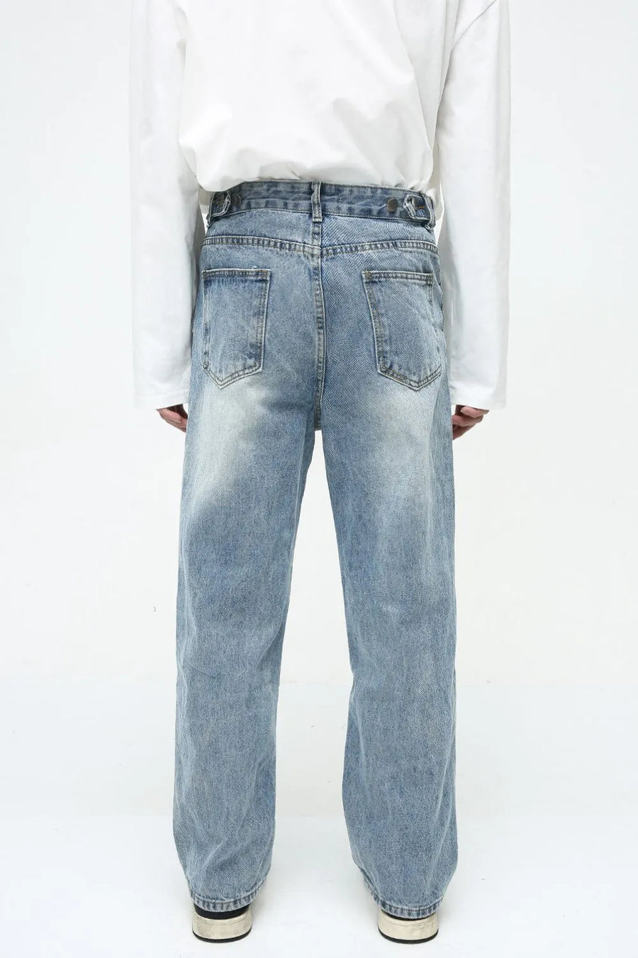 Vintage wash relaxed fit denim jeans in medium blue with button fly and adjustable waist tabs.