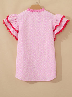 Pink eyelet embroidered blouse with flutter sleeves and red lace trim.