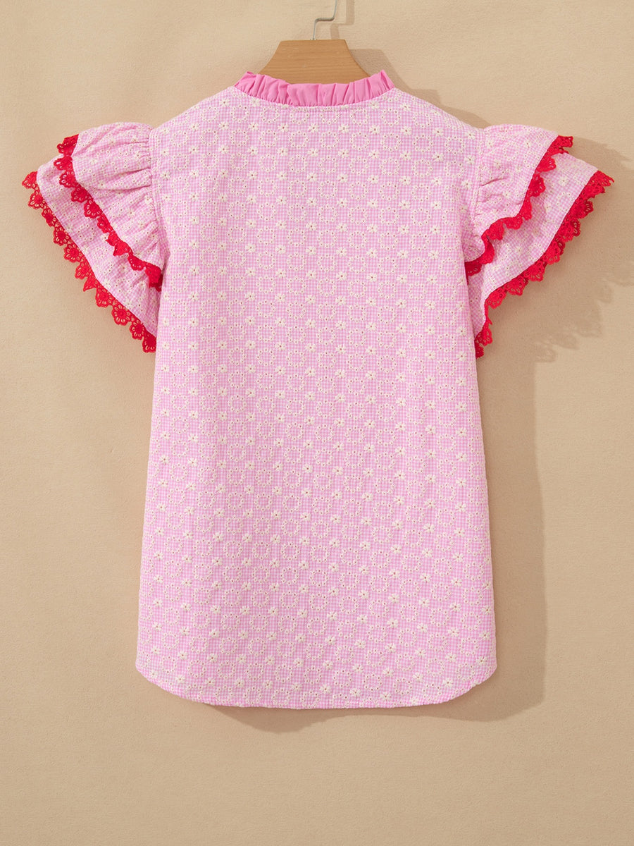 Pink eyelet embroidered blouse with flutter sleeves and red lace trim.