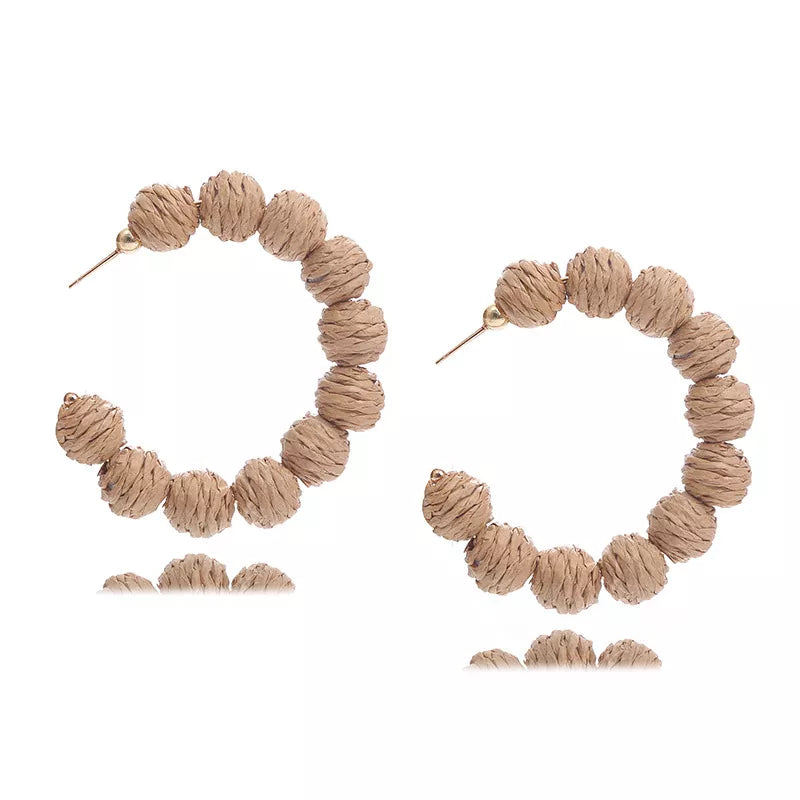 Beige raffia grass C-hoop earrings with textured beads and gold post detail.