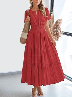 Rust V-neck tiered maxi dress with smocked waist and short sleeves, styled with a straw bag.