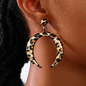Crescent dangle earrings in gold with leopard print pattern.