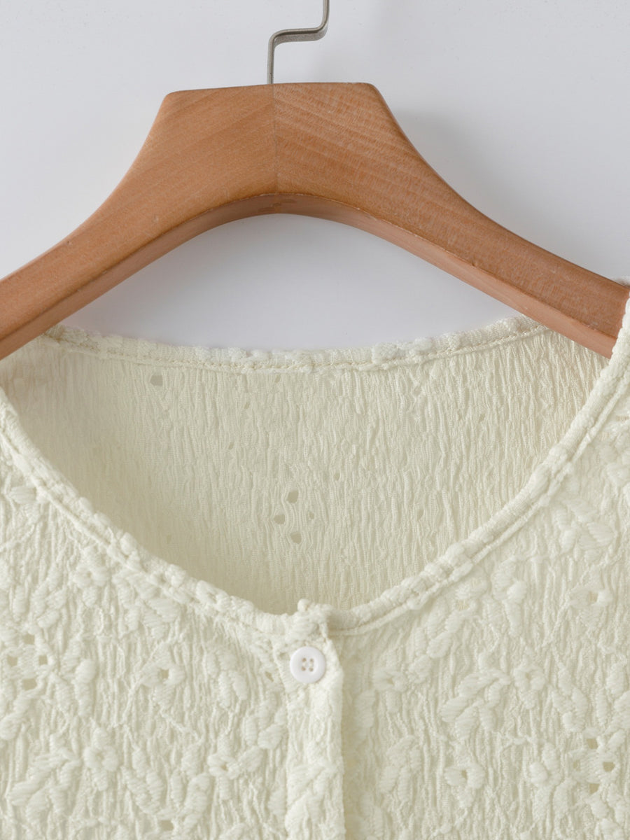 Cream lace button-up cardigan with textured fabric and delicate floral pattern.