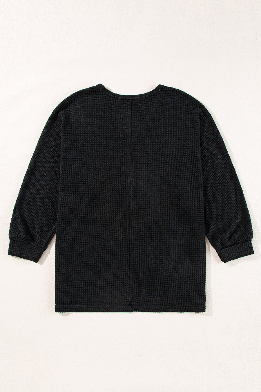 Black waffle knit V-neck top with long sleeves and a slit hem.